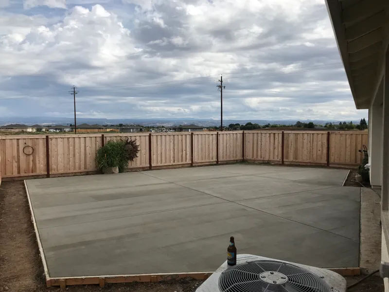 Freshly finished concrete patio in a fenced backyard