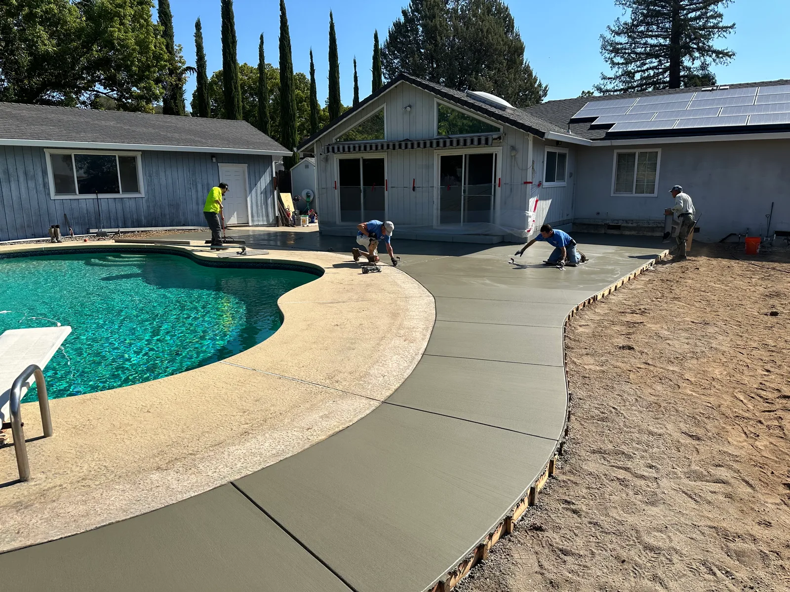 Curved concrete flatwork alongside a residential swimming pool