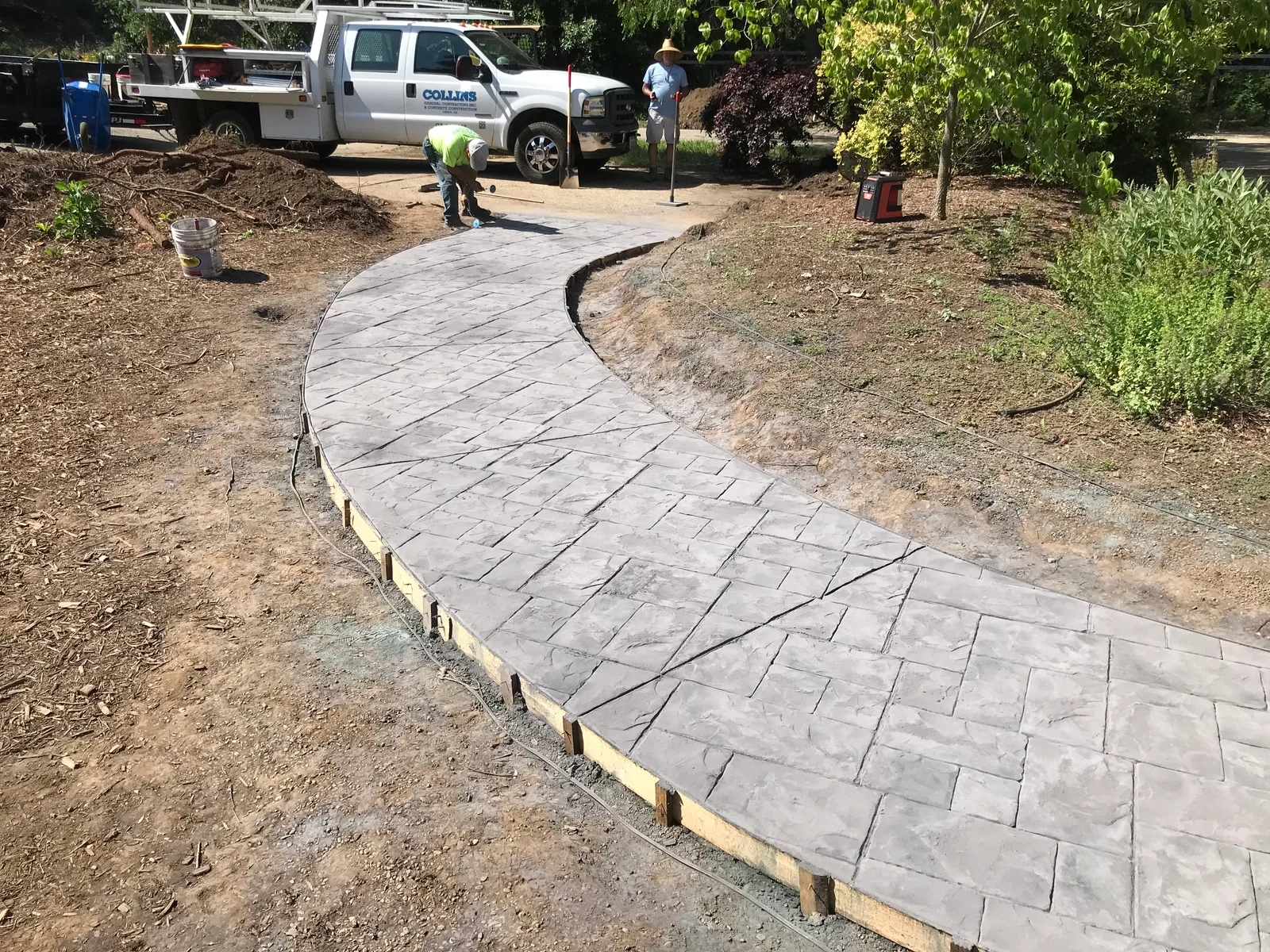 Curved textured concrete walkway through a landscaped yard